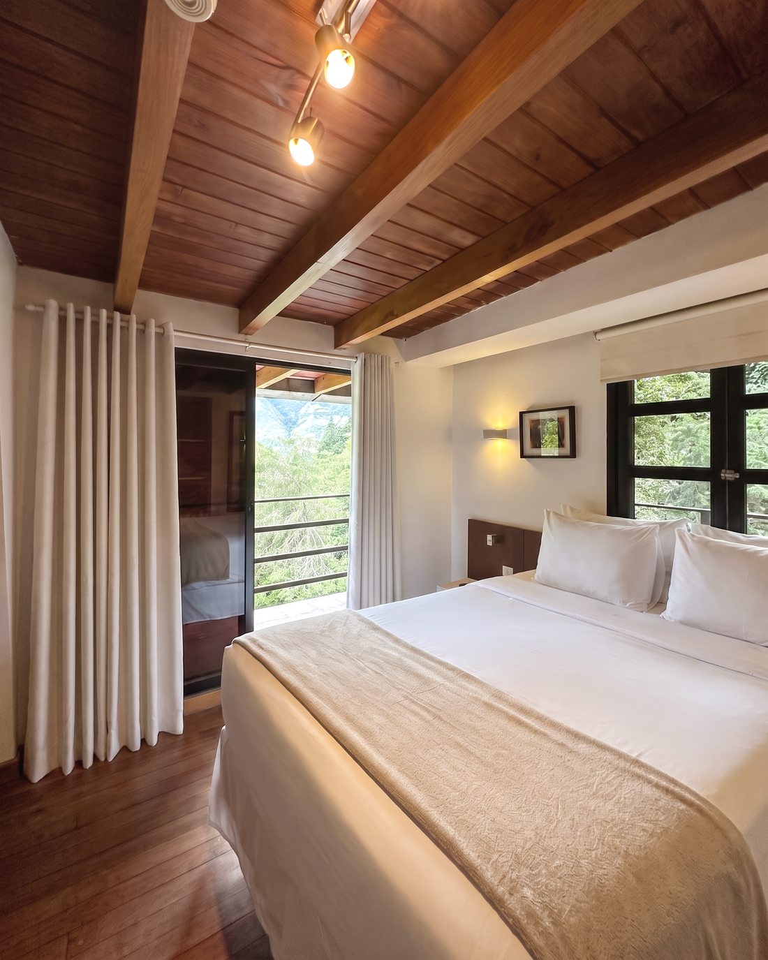 Habitación con cama grande y puerta al balcón, con la montaña al fondo
