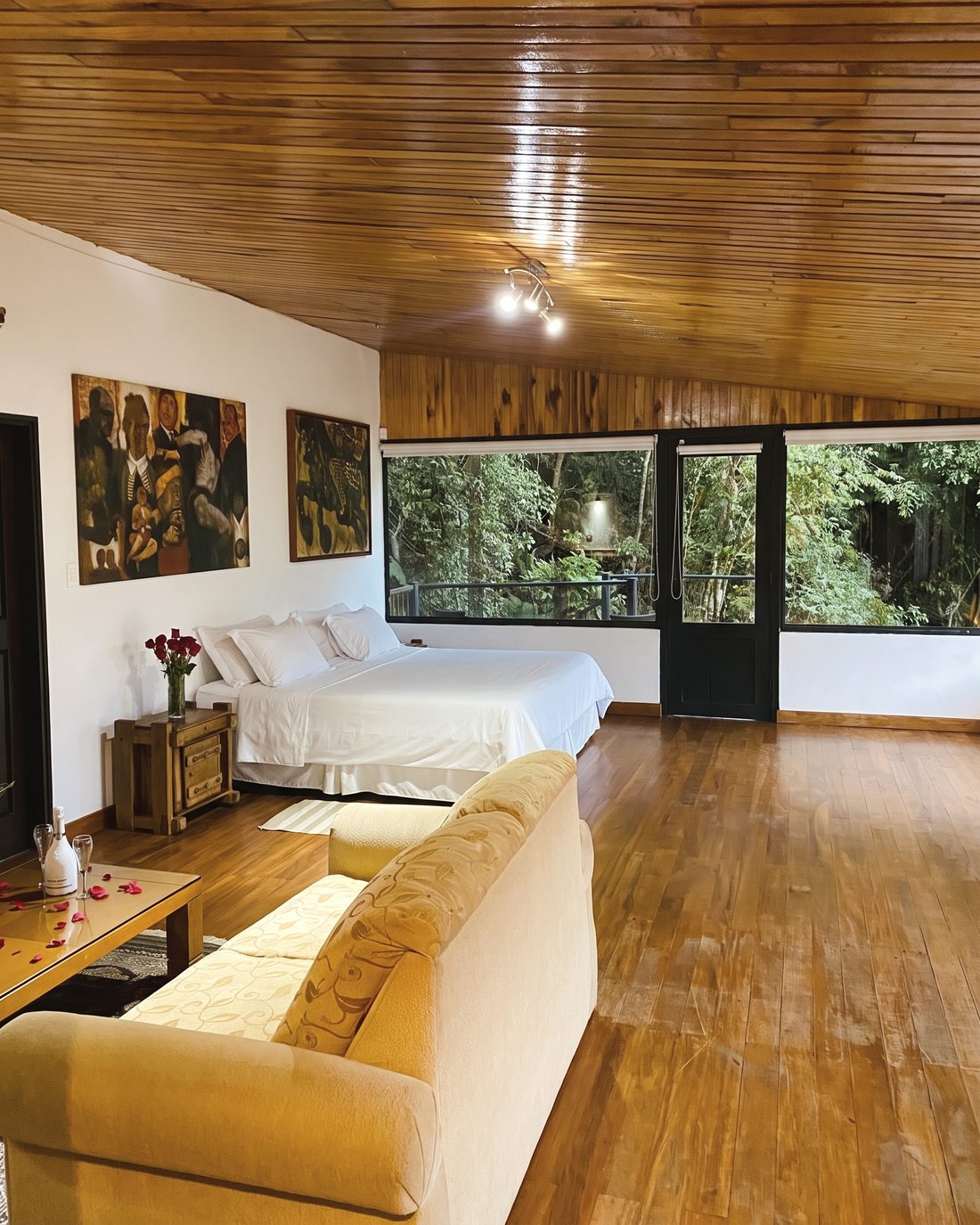Habitación amplia con sofá, obras de arte y ventanales al bosque